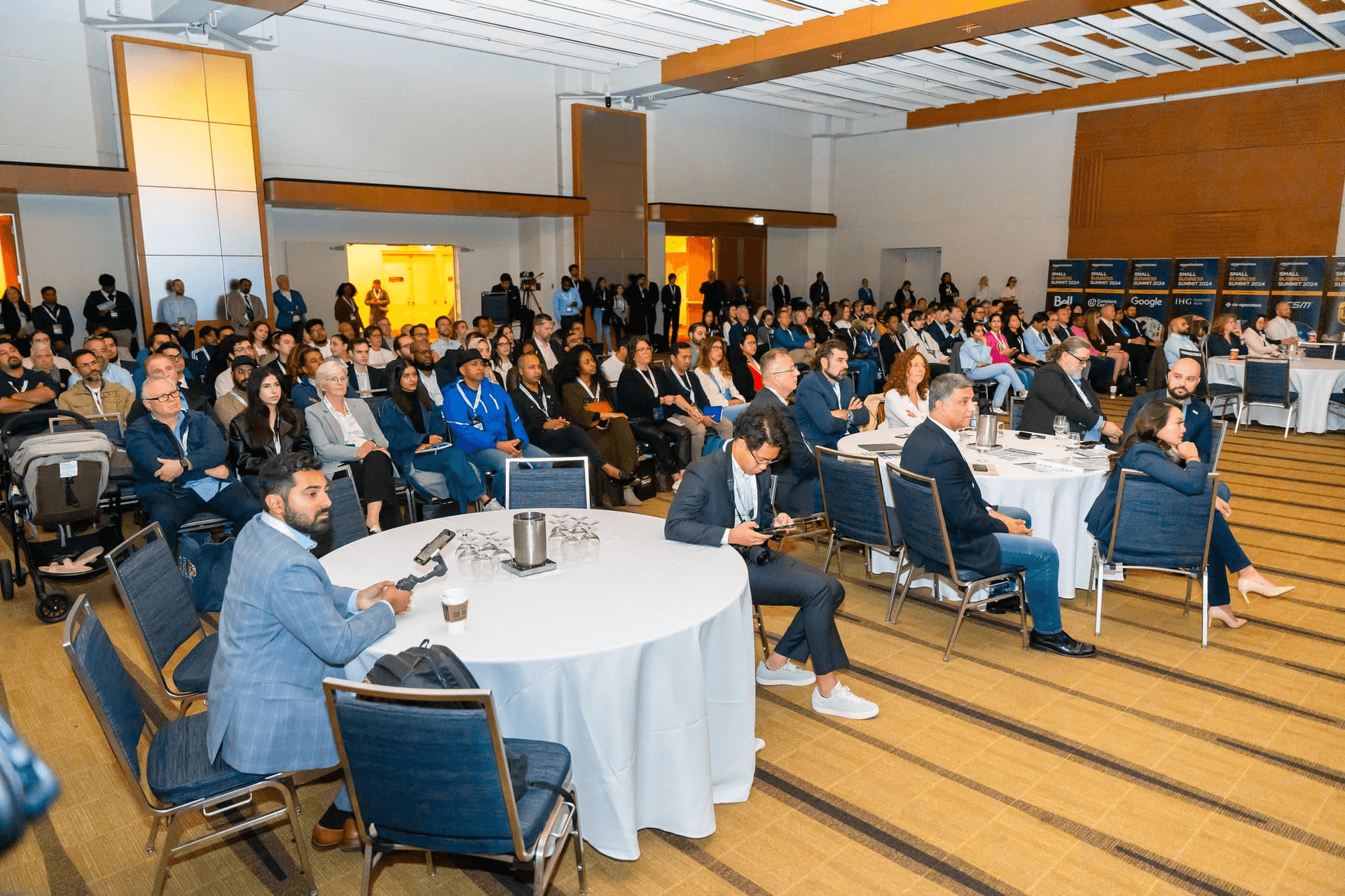Wide view of a full ballroom with roundtables and seated attendees